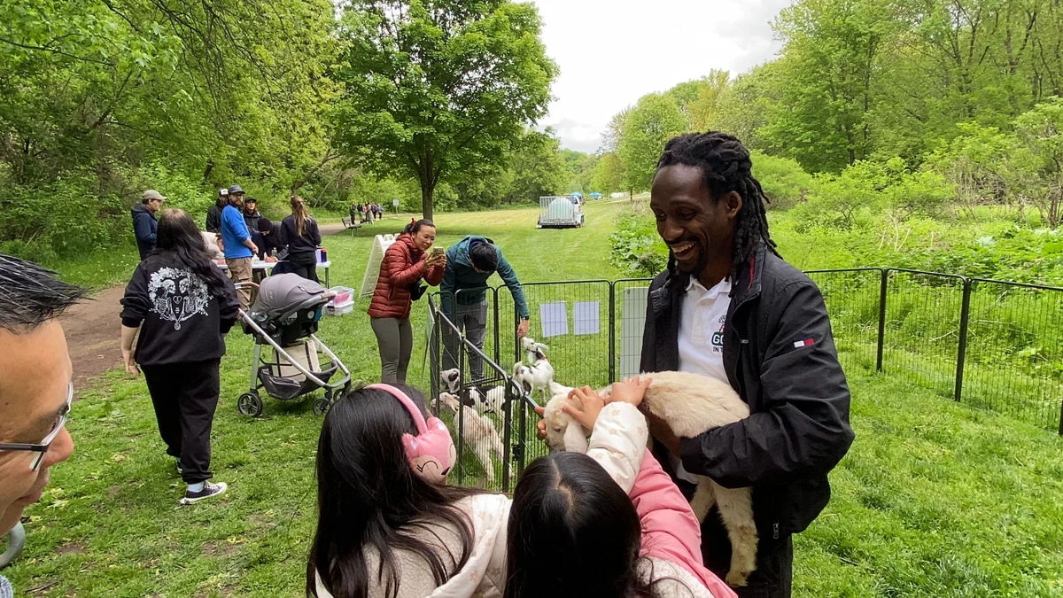 Children meet a baby goat held by a Goats in the City representative.